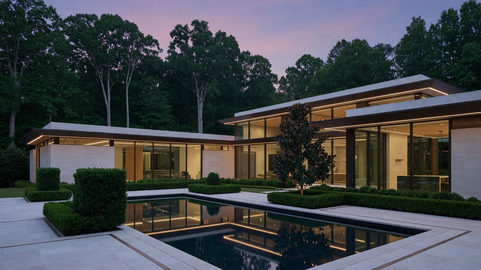 A Georgian brick estate at dusk with warm light in the windows and a long lawn